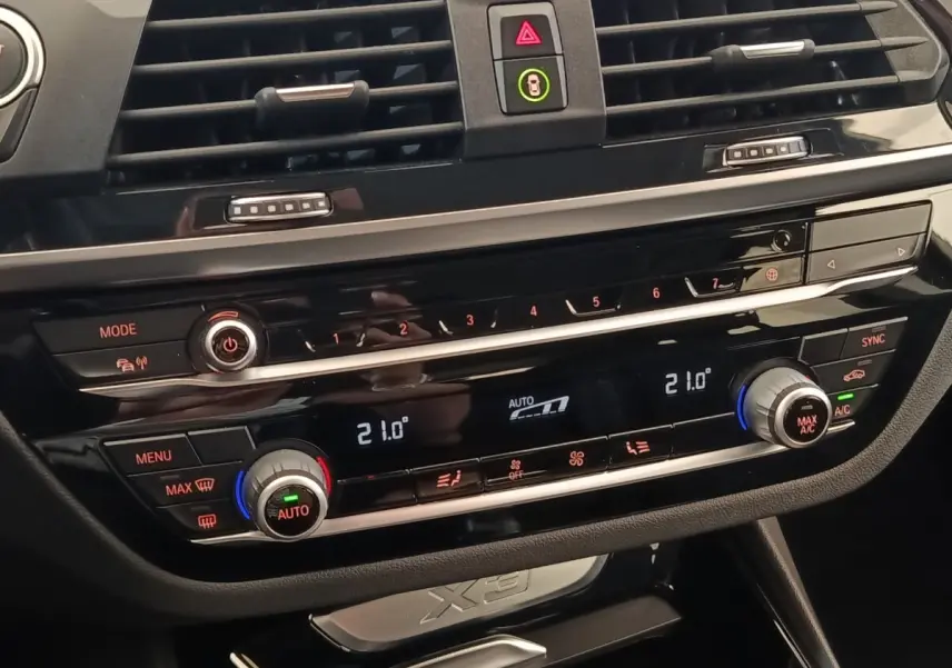 Détail de la console centrale noire du BMW X3 2020 avec commandes climatisation digitale et boutons multifonctions.