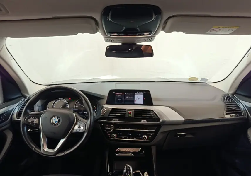 Vue intérieure avant du tableau de bord et volant cuir alu multifonctions d'une BMW X3 xDrive20d gris clair de 2020.