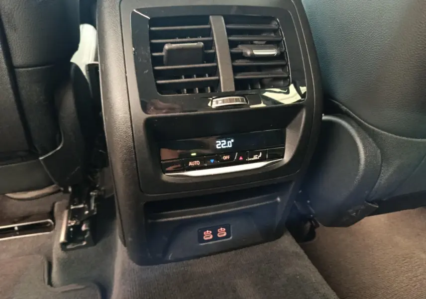 Vue rapprochée de la console arrière noire avec commandes climatisation et prises USB du BMW X3 gris clair 2020.