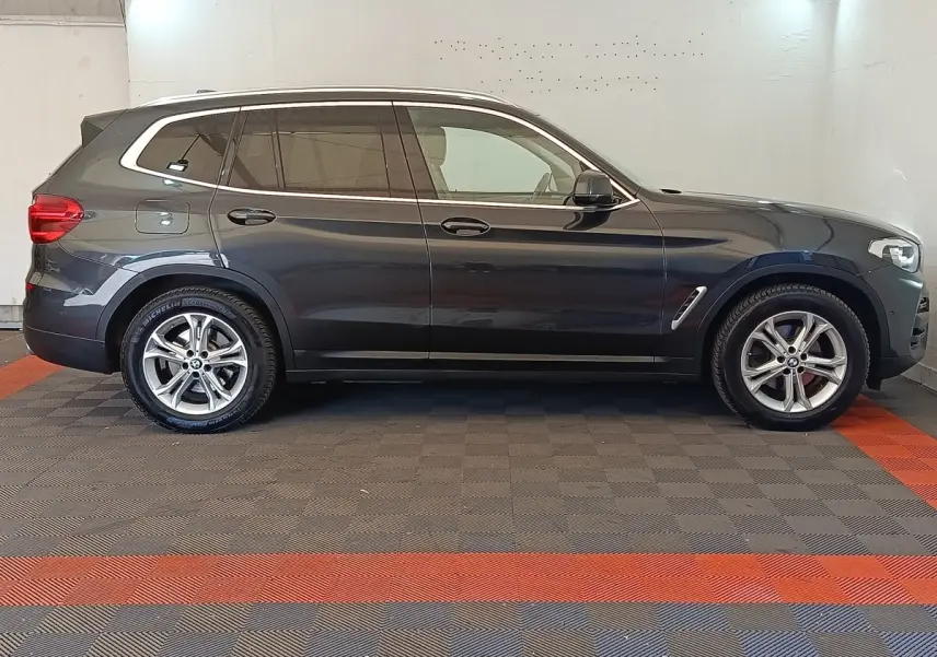 BMW X3 gris clair vue de profil côté gauche dans un garage avec jantes alliage et vitres teintées.