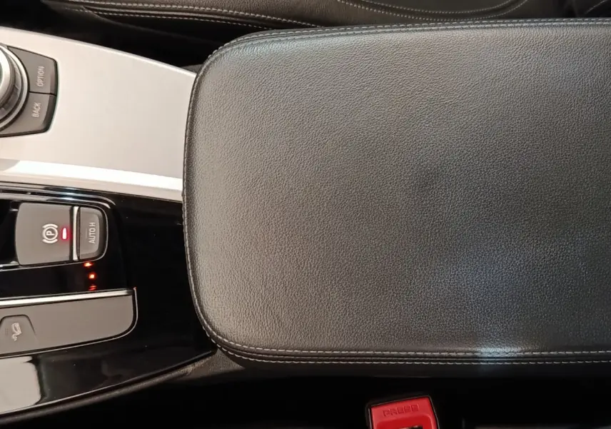 Gros plan sur la console centrale et accoudoir en cuir noir de la BMW X3 xDrive20d 2020, avec commandes électroniques visibles.
