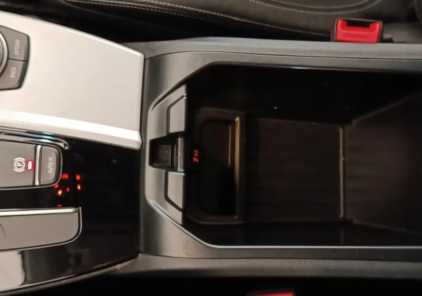 Vue rapprochée de la console centrale noire de la BMW X3 xDrive20d 2020 avec bouton frein à main électrique et rangement ouvert.
