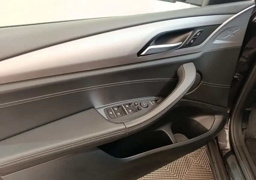 Vue rapprochée de la porte avant gauche de la BMW X3 gris clair, avec commandes vitres et insert alu.