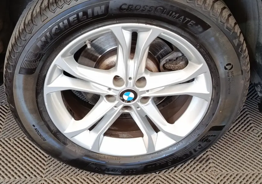 Gros plan sur la jante argentée BMW avec pneu Michelin CrossClimate 2, montrant le logo au centre.