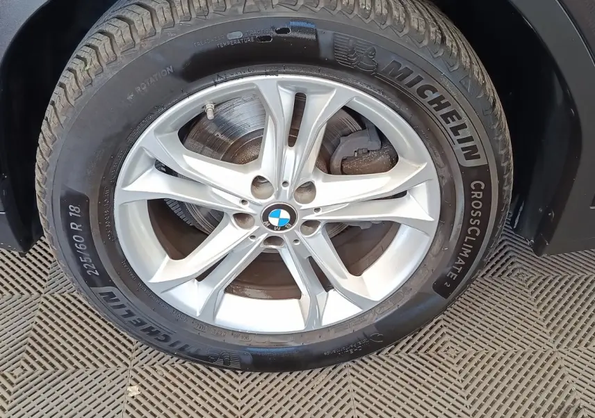 Gros plan sur la roue avant droite d'une BMW X3 gris clair avec jante alliage et pneu Michelin CrossClimate.