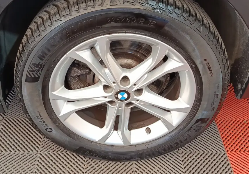 Gros plan sur la roue avant droite d’un BMW X3 gris clair, jante alliage 5 branches et pneu Michelin.
