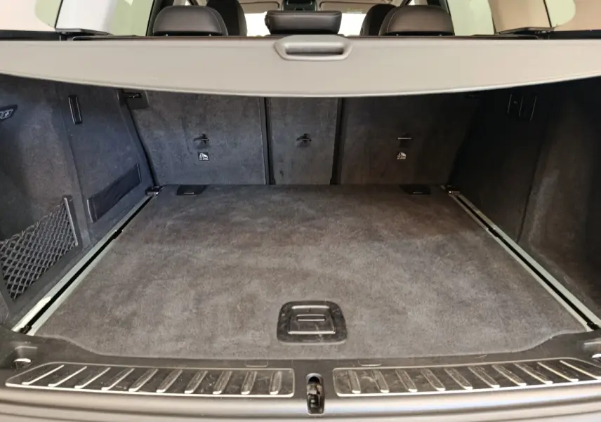 Coffre spacieux de BMW X3 gris clair vu de l'arrière avec banquette rabattable et filet de sécurité visible.