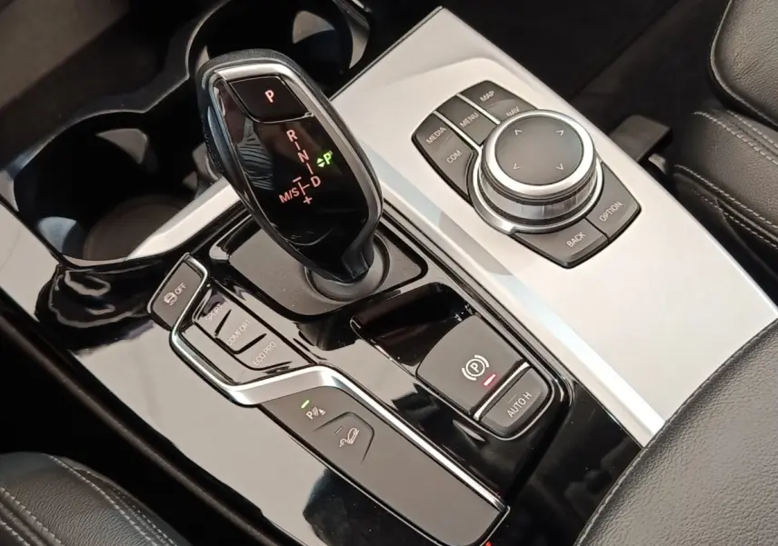 Gros plan sur la console centrale noire et argentée avec levier de vitesse et commandes du BMW X3 gris clair 2020.