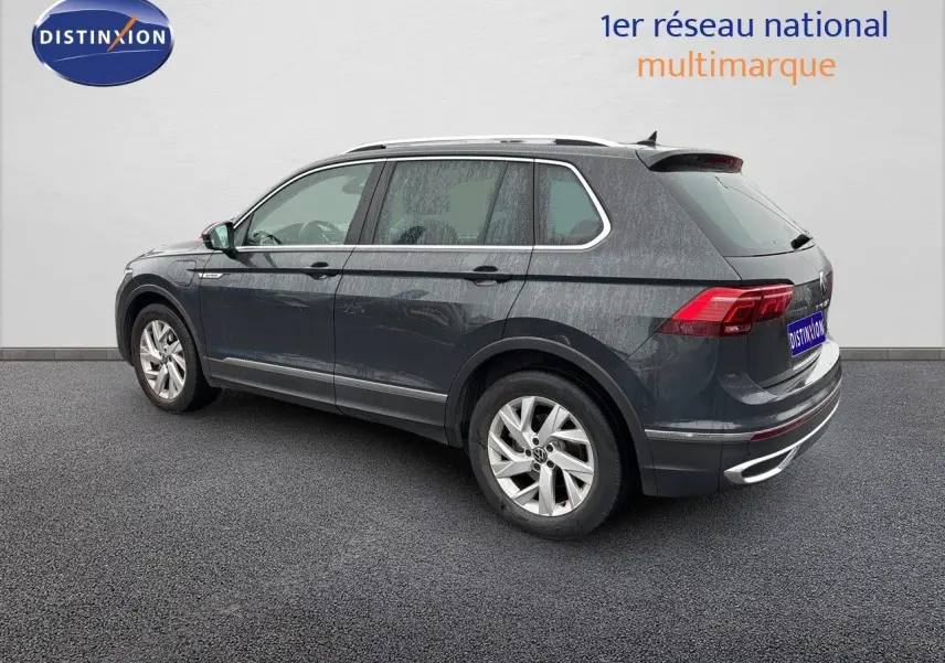 Vue 3/4 arrière côté gauche d'un Volkswagen Tiguan gris lunaire hybride rechargeable de 2022 avec jantes alliage.