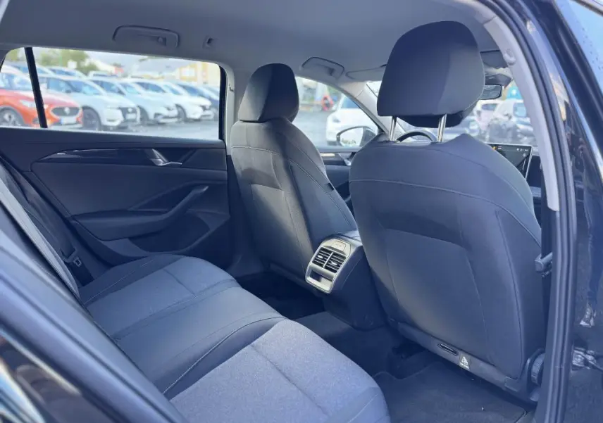 Vue intérieure arrière droite de la Volkswagen Passat SW noire 2024, montrant les sièges et la console centrale avec aérateurs.