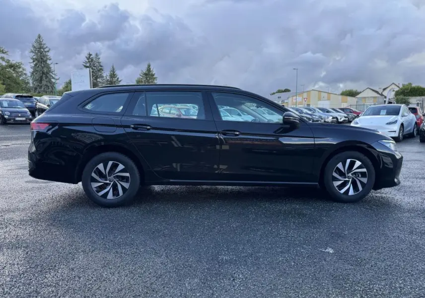 Profil côté droit d'une Volkswagen Passat SW noire 2024, avec jantes alliage et lignes élégantes sur parking extérieur.
