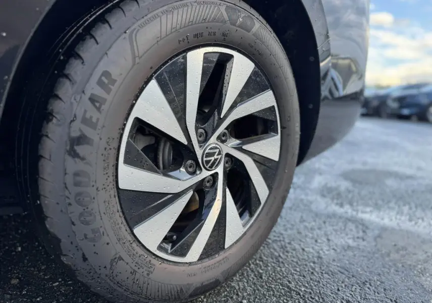 Gros plan sur la roue avant droite noire d'une Volkswagen Passat SW 2024 avec jante alliage bicolore et pneus Goodyear.