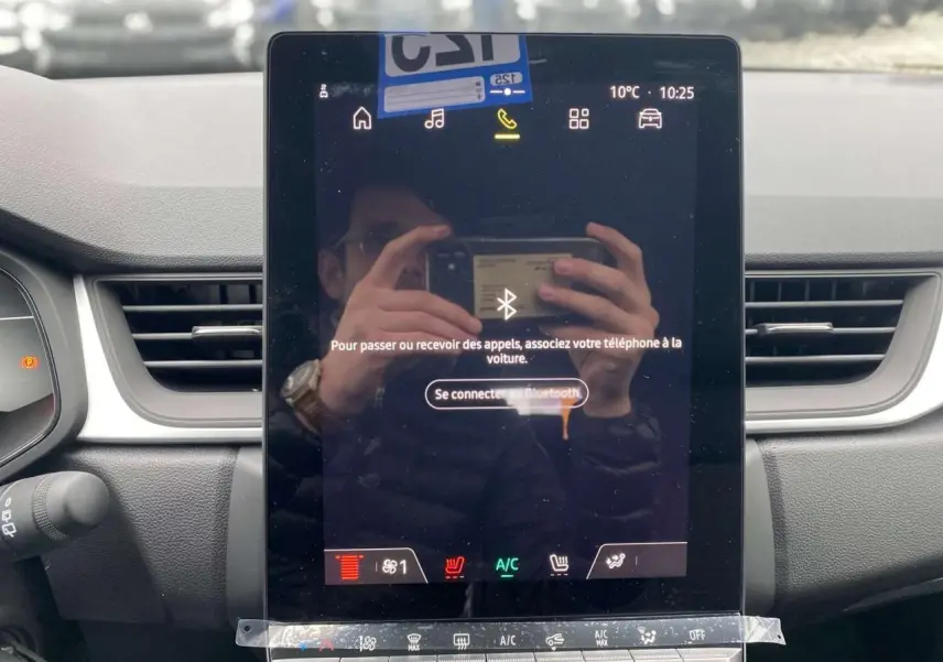 Écran tactile central du tableau de bord du Renault Captur 2025, avec commandes climatisation et ventilation visibles.