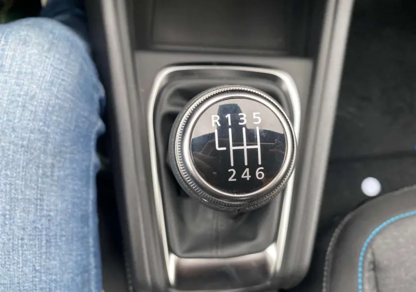 Gros plan sur le levier de vitesses manuel noir du Renault Captur 2025, avec couture bleue visible sur le siège à droite.