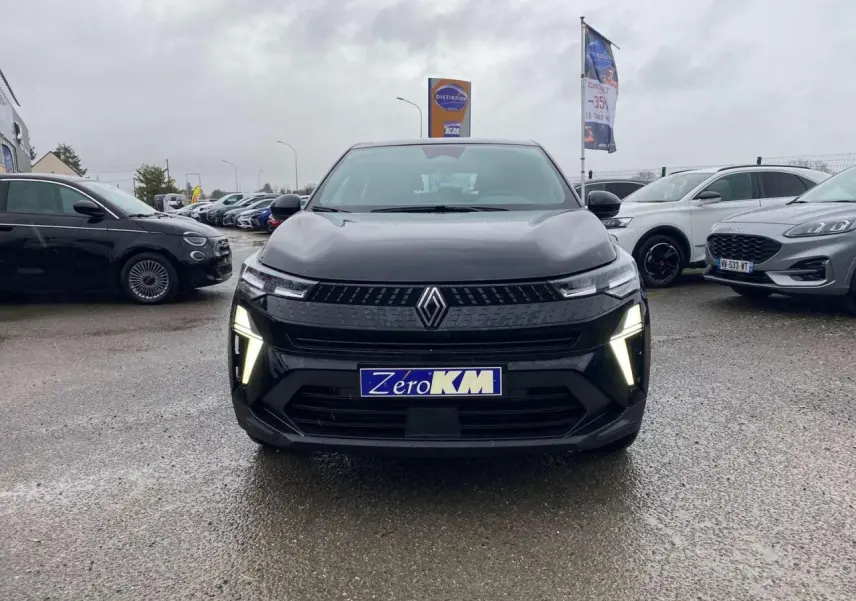 Vue avant d'un Renault Captur 2025 noir étoilé avec feux LED allumés sur un parking humide.