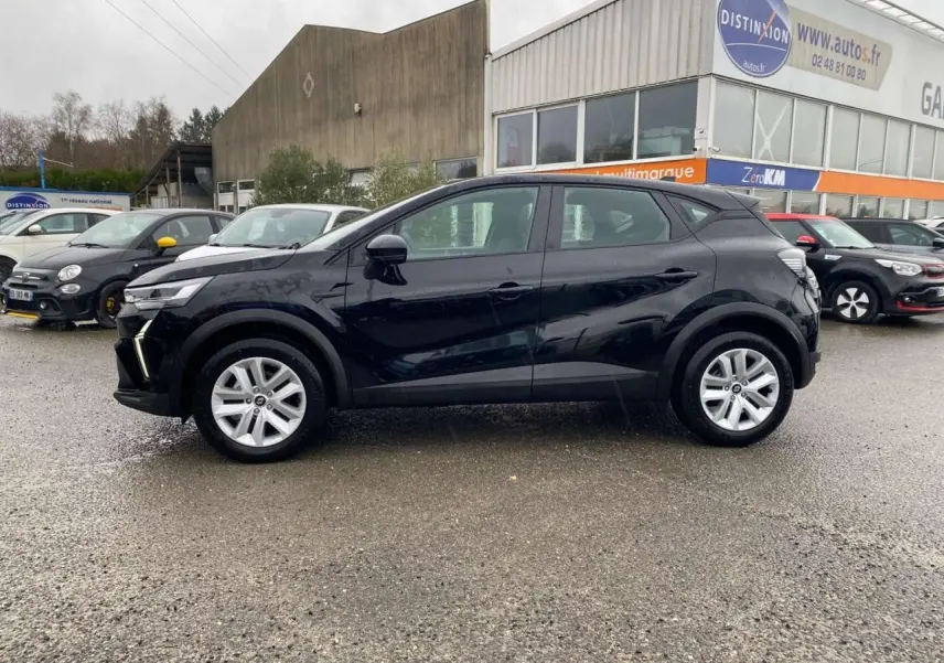 Profil côté gauche d'un Renault Captur noir étoilé 2025 garé devant un garage avec jantes argentées.