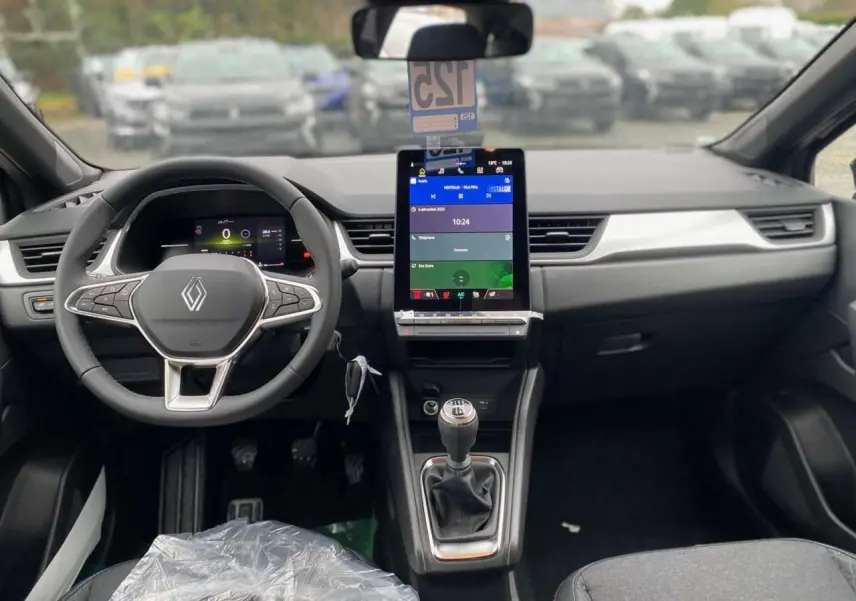 Vue intérieure frontale du tableau de bord du Renault Captur noir étoilé 2025 avec écran tactile vertical et boîte manuelle.