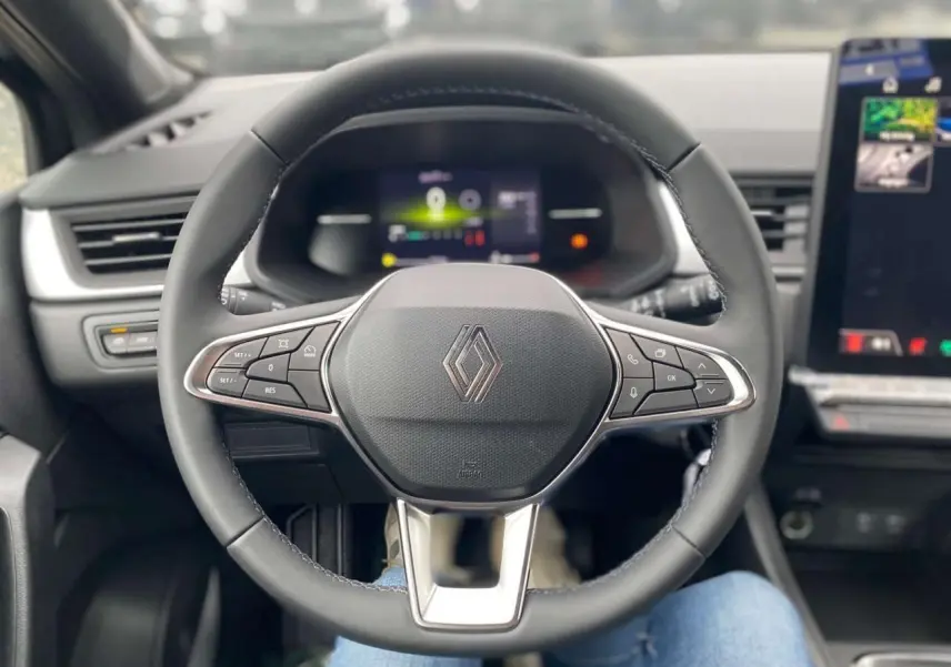 Vue centrée sur le volant noir du Renault Captur 2025 avec commandes intégrées et tableau de bord numérique flou.
