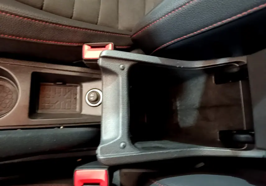 Vue plongeante sur le rangement central ouvert et les sièges noirs avec surpiqûres rouges d’un SEAT Arona bleu 2022.