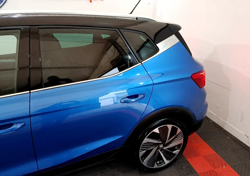 Vue côté droit arrière du SEAT Arona bleu 2022 avec jante alliage et toit noir contrasté.