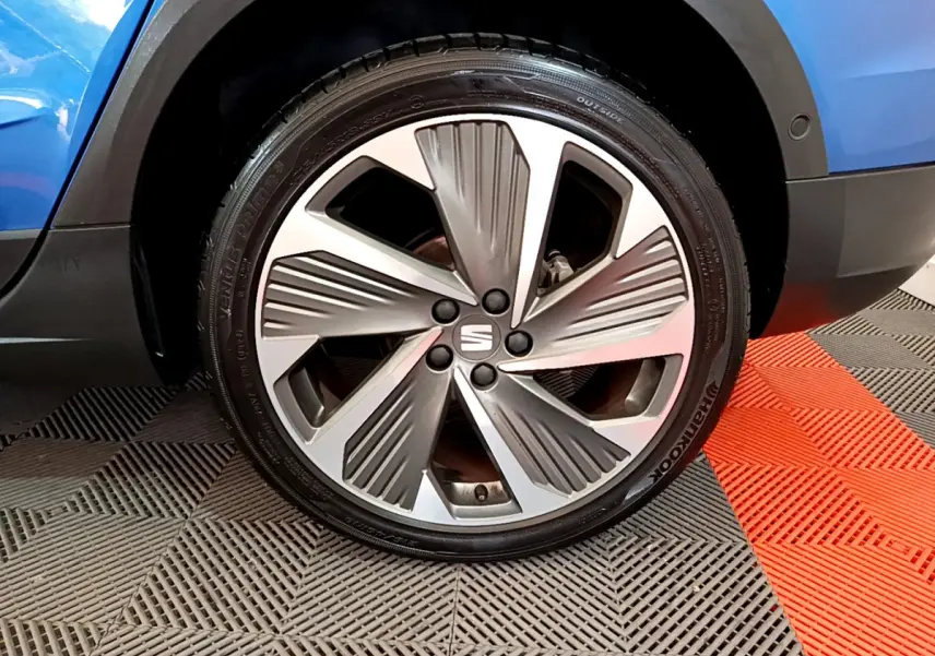 Gros plan sur la roue avant droite d'une SEAT Arona bleu 2022 avec jante alliage au design moderne.