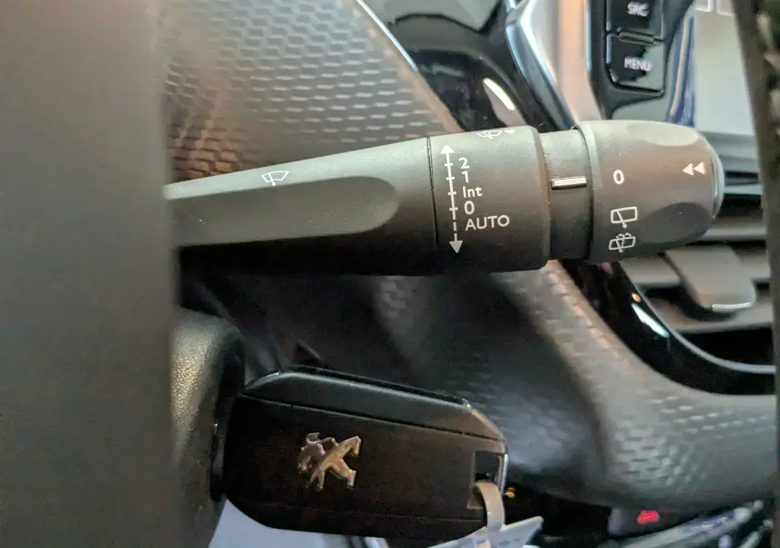 Gros plan sur la manette d’essuie-glace et la clé de contact noire avec logo Peugeot dans un Peugeot 2008 blanc de 2017.