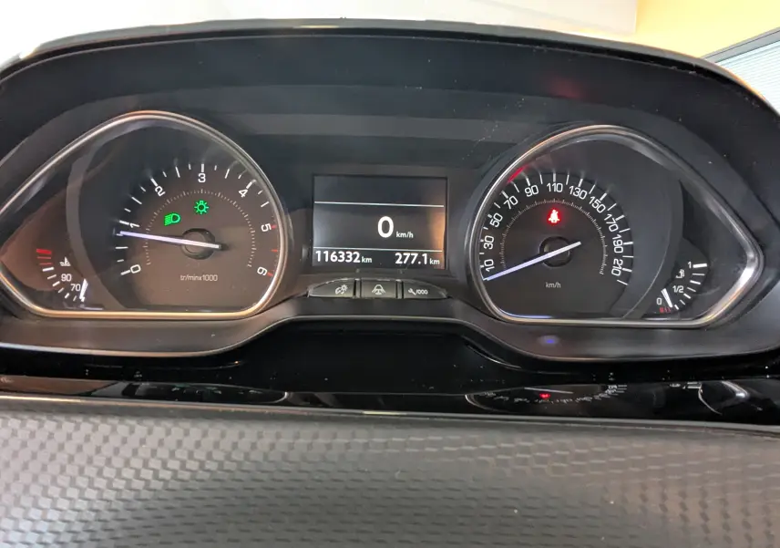 Vue rapprochée du tableau de bord du Peugeot 2008 blanc, affichant le compteur de vitesse et le compte-tours allumés.