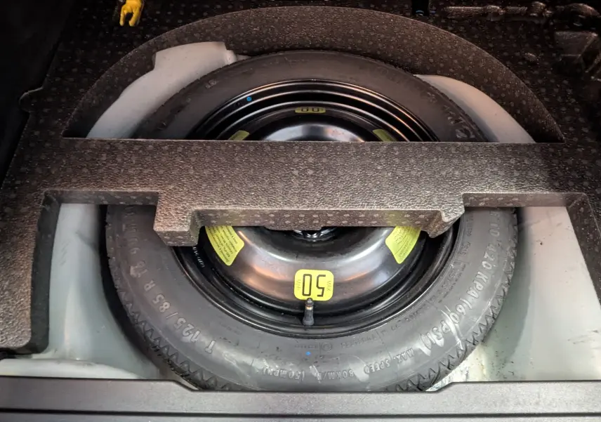 Vue rapprochée de la roue de secours noire dans le coffre d'une Peugeot 2008 blanche de 2017.