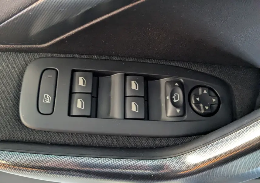 Gros plan sur les commandes électriques des vitres et des rétroviseurs côté conducteur d'une Peugeot 2008 blanche de 2017.