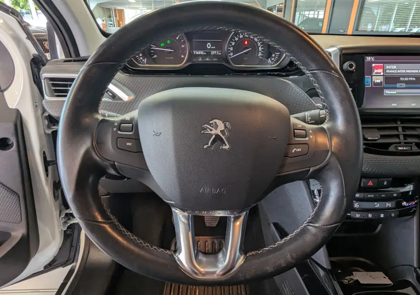 Vue centrée sur le volant en cuir noir du Peugeot 2008 blanc de 2017, avec tableau de bord et écran multimédia visibles.