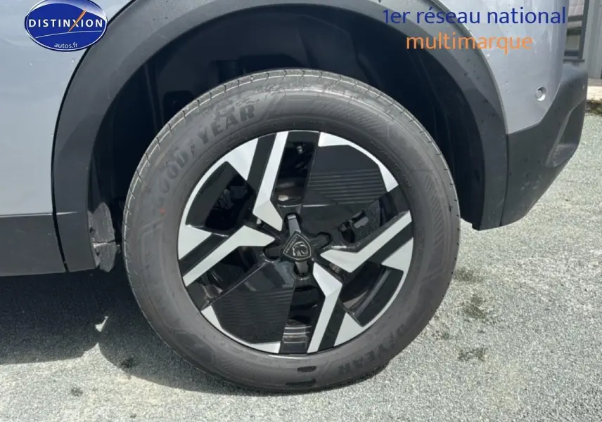 Gros plan sur la roue avant droite du Peugeot 2008 gris artense avec jante alu bicolore et logo Peugeot central.