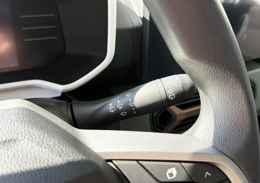 Gros plan sur la commande d’essuie-glace à gauche du volant dans l’habitacle du Dacia Spring 65 Extreme bleu ardoise 2026.