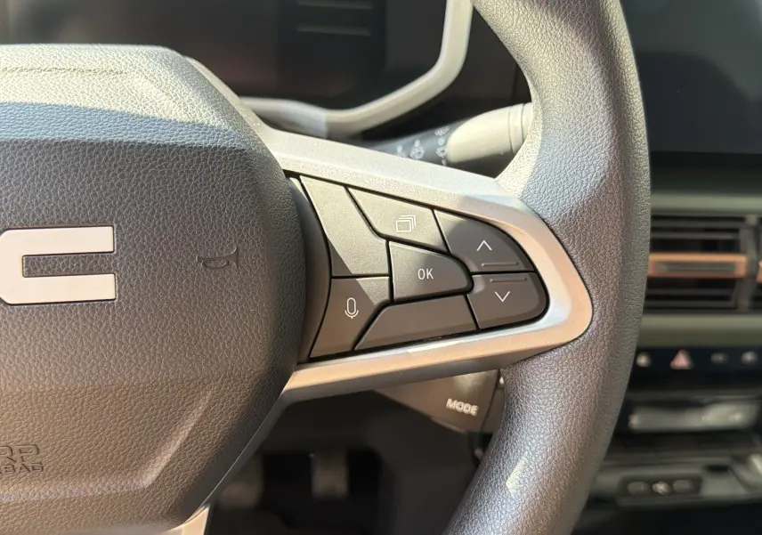 Gros plan sur le volant côté droit du Dacia Spring 65 Extreme 2026, avec commandes intégrées et finition noire.