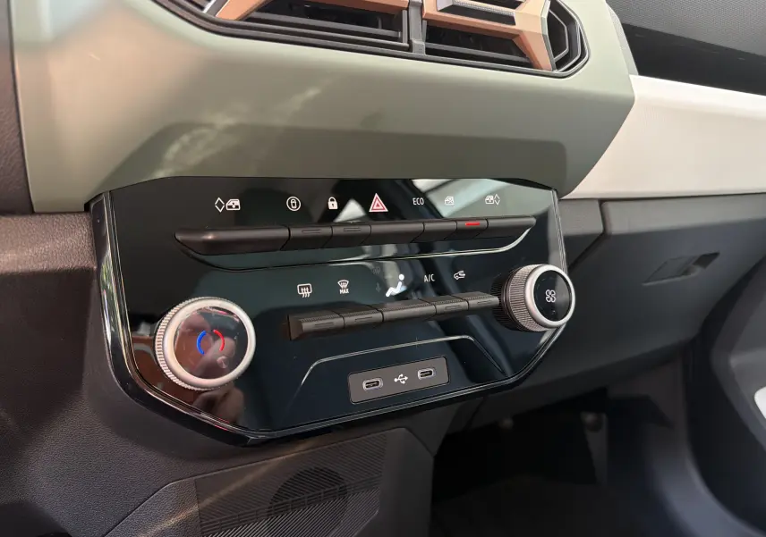 Vue rapprochée de la console centrale noire brillante du Dacia Spring 65 Extreme 2026 avec commandes climatisation et ports USB.