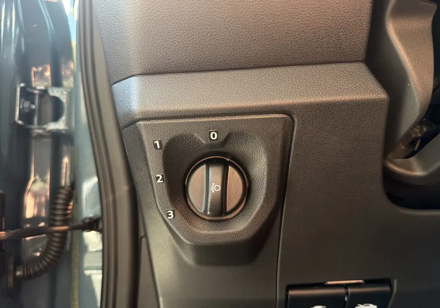 Détail du réglage d’inclinaison des phares sur la console côté gauche d’une Dacia Spring 65 Extreme bleu ardoise 2026.