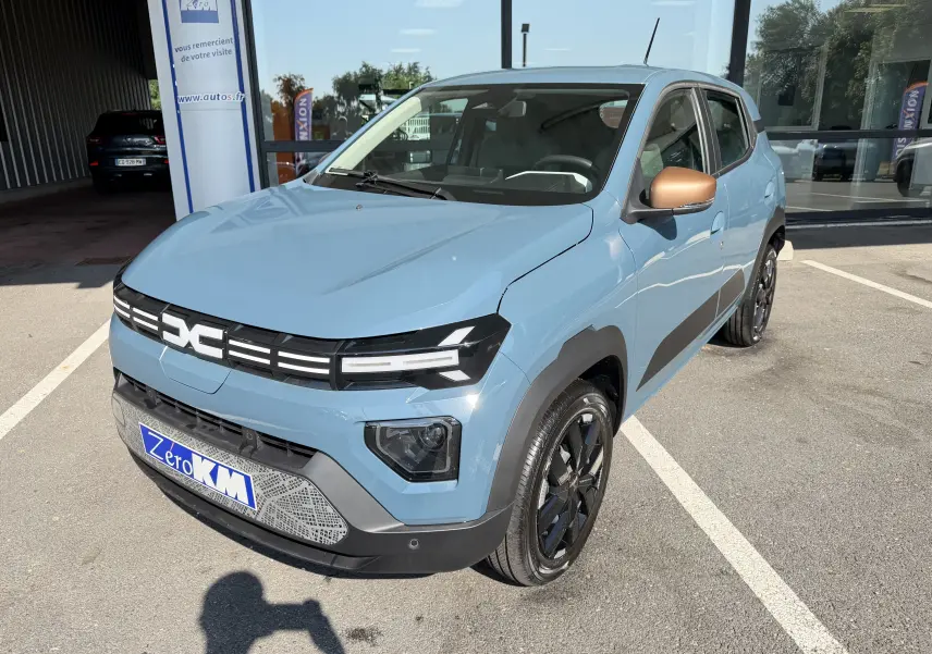 Dacia Spring 65 Extreme bleu ardoise en 3/4 avant droit, avec rétroviseurs bronze et jantes noires brillantes.
