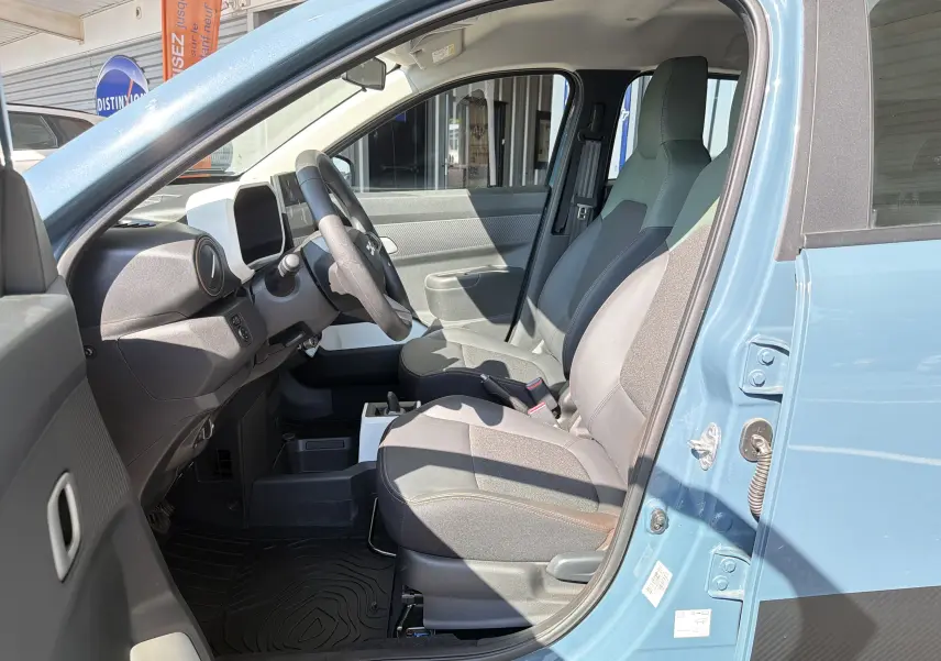 Intérieur de la Dacia Spring 65 Extreme 2026 bleu ardoise, vue côté conducteur avec sièges et tableau de bord visibles.