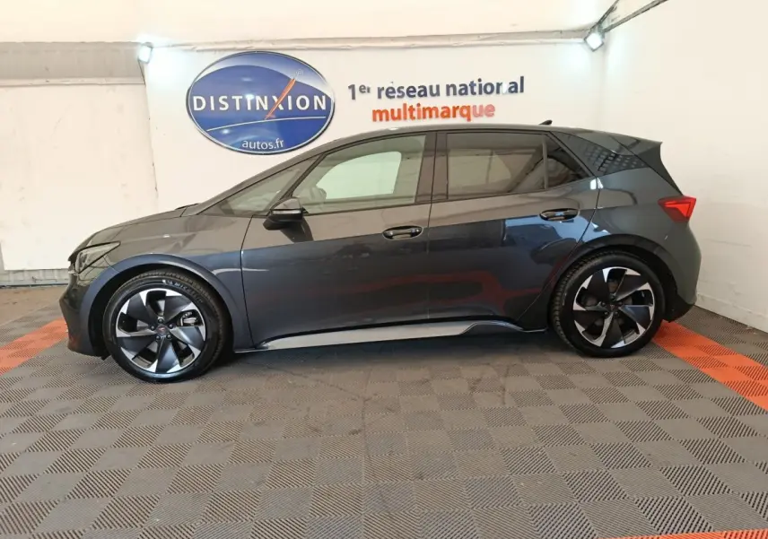Vue de profil côté gauche d'une CUPRA BORN 230ch gris foncé, avec jantes noires et détails sportifs visibles.
