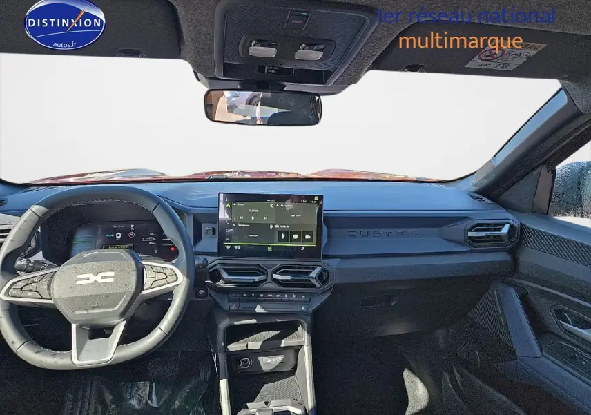 Vue intérieure avant du tableau de bord noir du Dacia Duster 2025 avec écran tactile et volant multifonction.