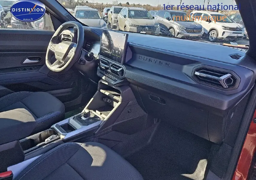 Intérieur avant droit du Dacia Duster 2025 avec tableau de bord noir et écran tactile central visible.
