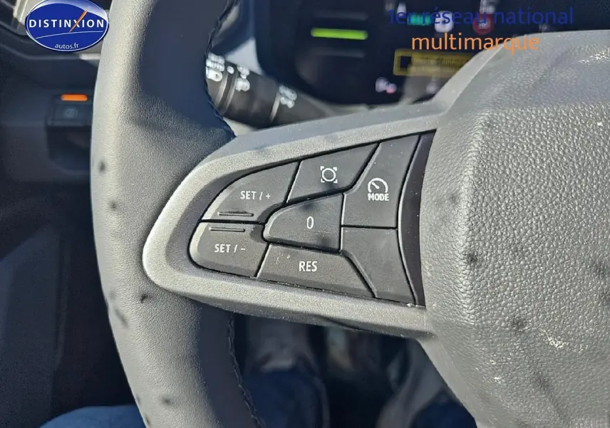 Gros plan sur les commandes du volant côté gauche du Dacia Duster brun terracotta 2025, mode cruise control visible.