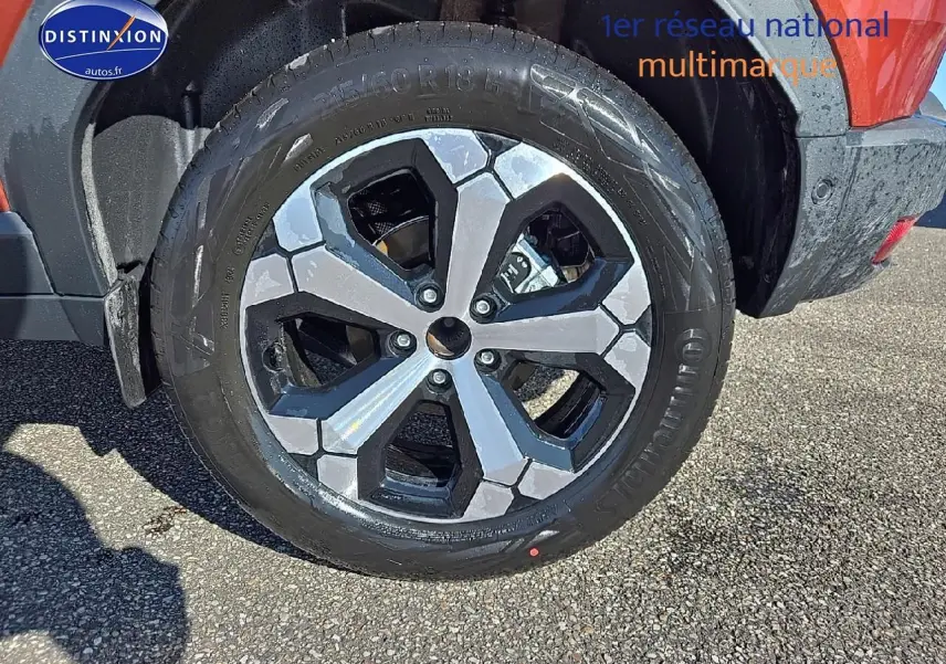 Gros plan sur la jante alu noire et argent du Dacia Duster brun terracotta, côté arrière droit du véhicule.