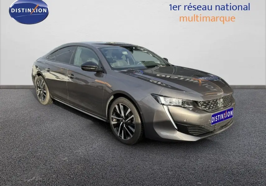 Peugeot 508 gris platinium vue 3/4 avant droit, avec jantes alliage noires et calandre distinctive.