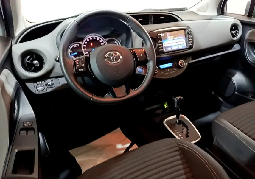Vue intérieure de la Toyota Yaris 2020, tableau de bord et volant cuir noir avec écran tactile central allumé.