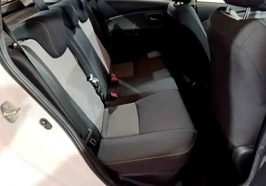 Vue intérieure côté gauche montrant la banquette arrière bicolore gris et noir de la Toyota Yaris blanche 2020 hybride.