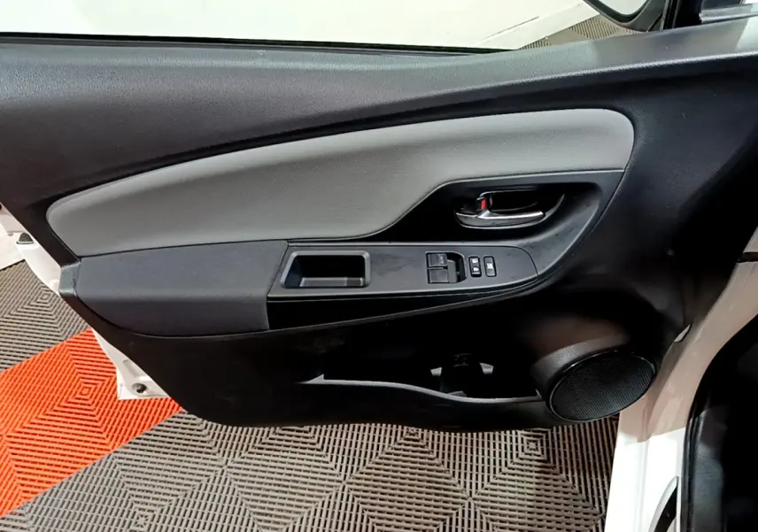 Vue rapprochée de la porte avant gauche blanche d'une Toyota Yaris 1.5 Hybride 2020 avec commandes de vitres et poignée noire.