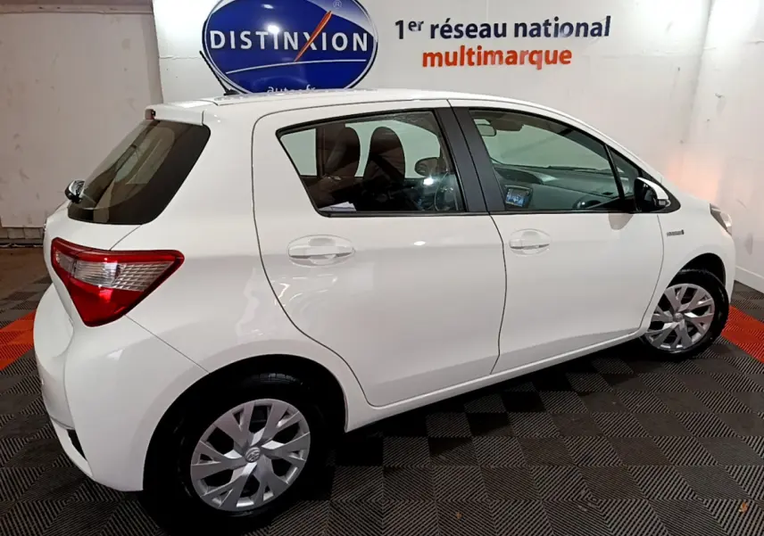 Vue de profil côté gauche d'une Toyota Yaris blanche 1.5 Hybride 100h France Business de 2020 en intérieur showroom.