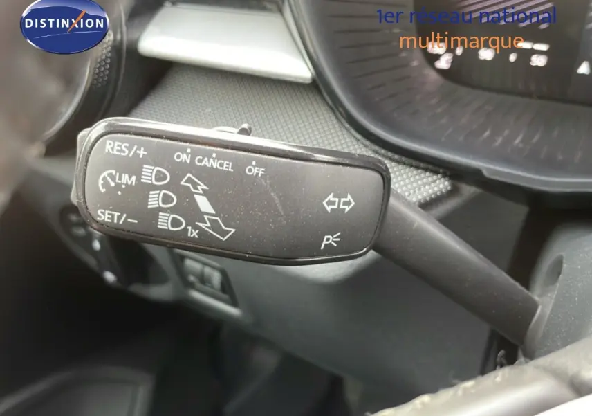 Gros plan sur le commodo de régulateur de vitesse dans l’habitacle gris noir d’une Skoda Fabia blanche.