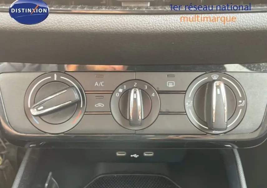 Gros plan sur les commandes de climatisation manuelle d'une Skoda Fabia blanche glacier, avec boutons rotatifs et ports USB visibles.