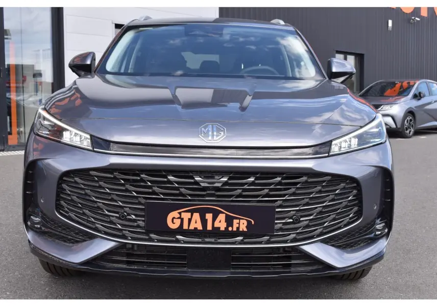 Vue frontale d’un MG MOTOR EHS gris 2026 avec calandre large noire et phares LED fins allumés.